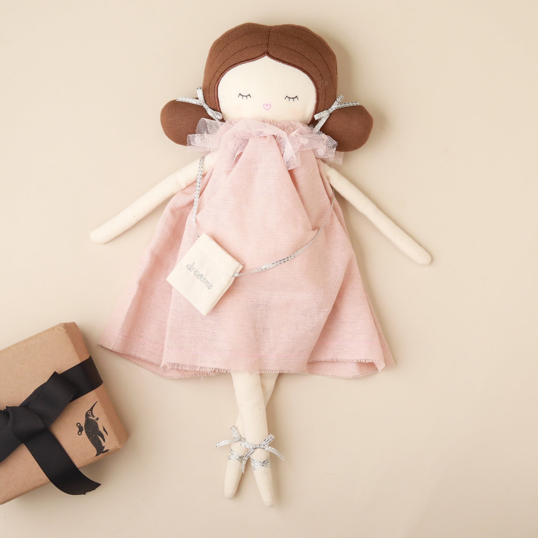 Handmade doll with a pink dress and brown hair on a beige background