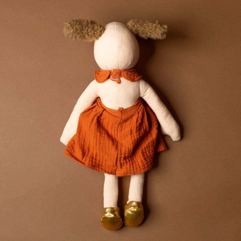 amy-the-puppy Stuffed animal toy with a back, orange outfit, and gold shoes on a brown background
