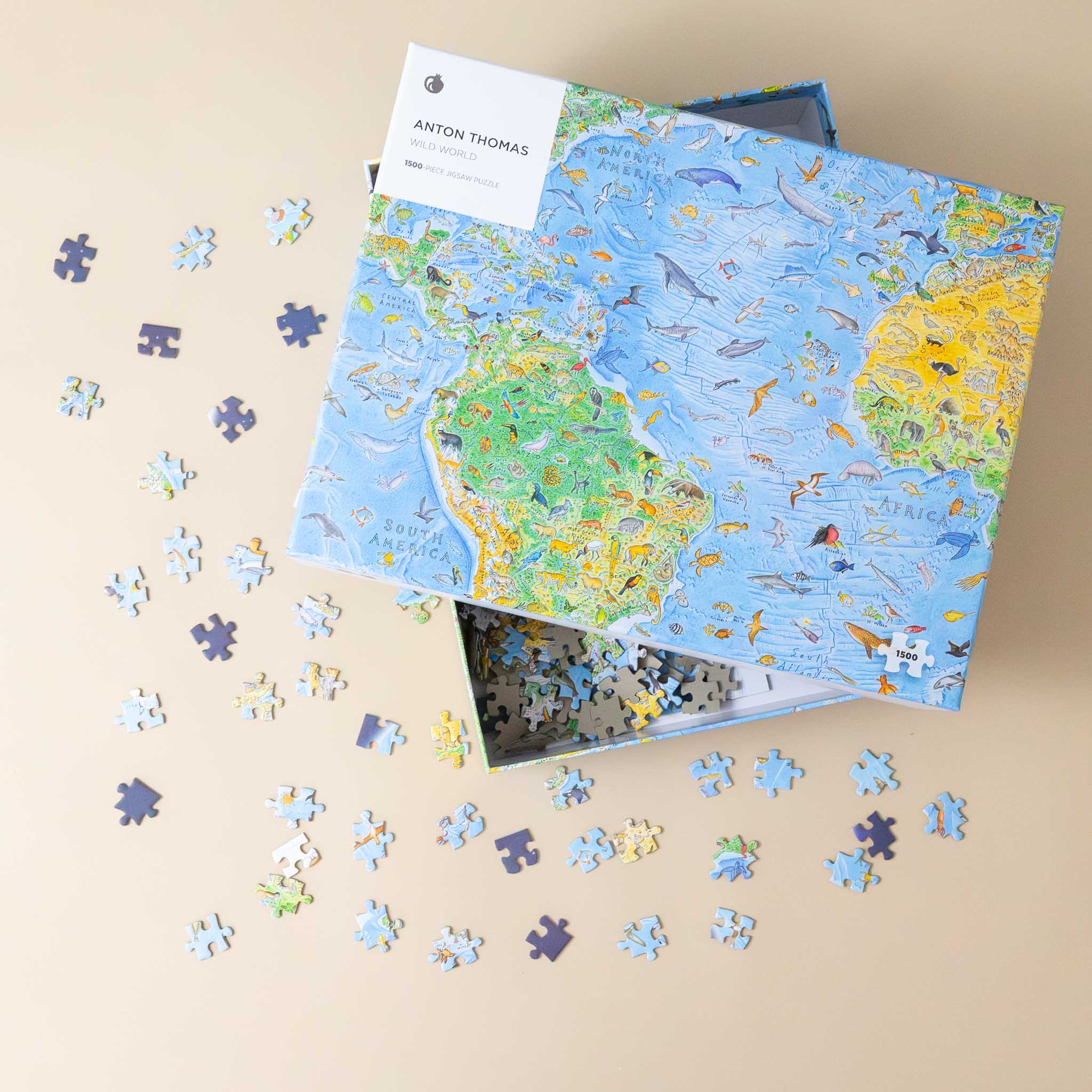 anton-thomas-1500-piece-wild-world-puzzle World map puzzle with pieces scattered on a beige surface