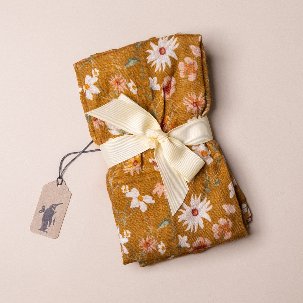bamboo-burpie-set-wildflowers Folded fabric with floral pattern and ribbon on a beige background