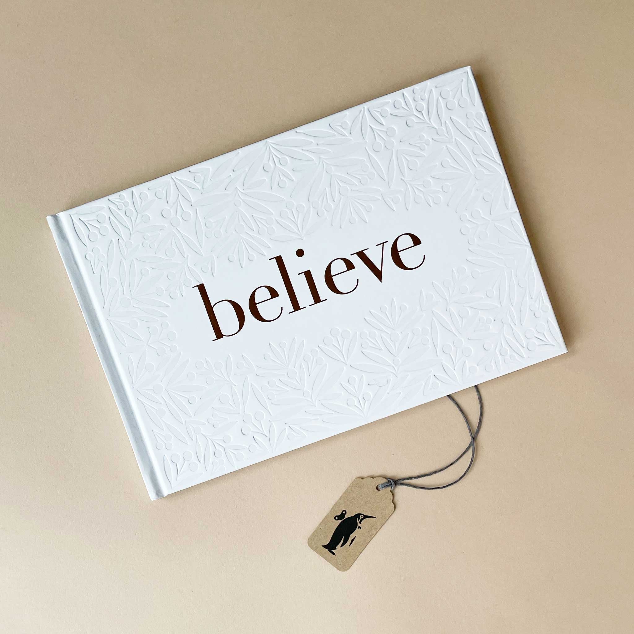 White textured book with 'believe' text on a beige background