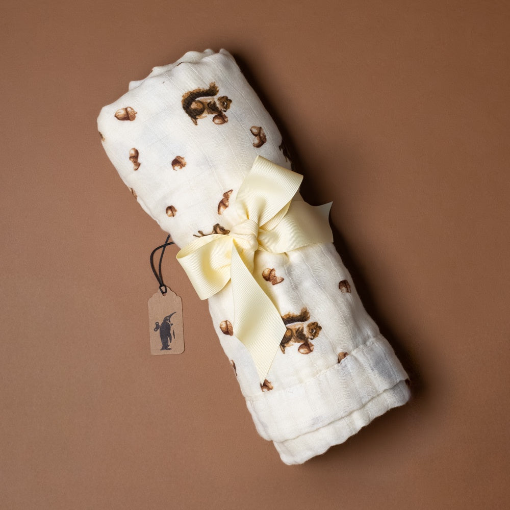 big-lovie-chipmunk Rolled-up white blanket with brown patterns and a yellow bow on a brown background