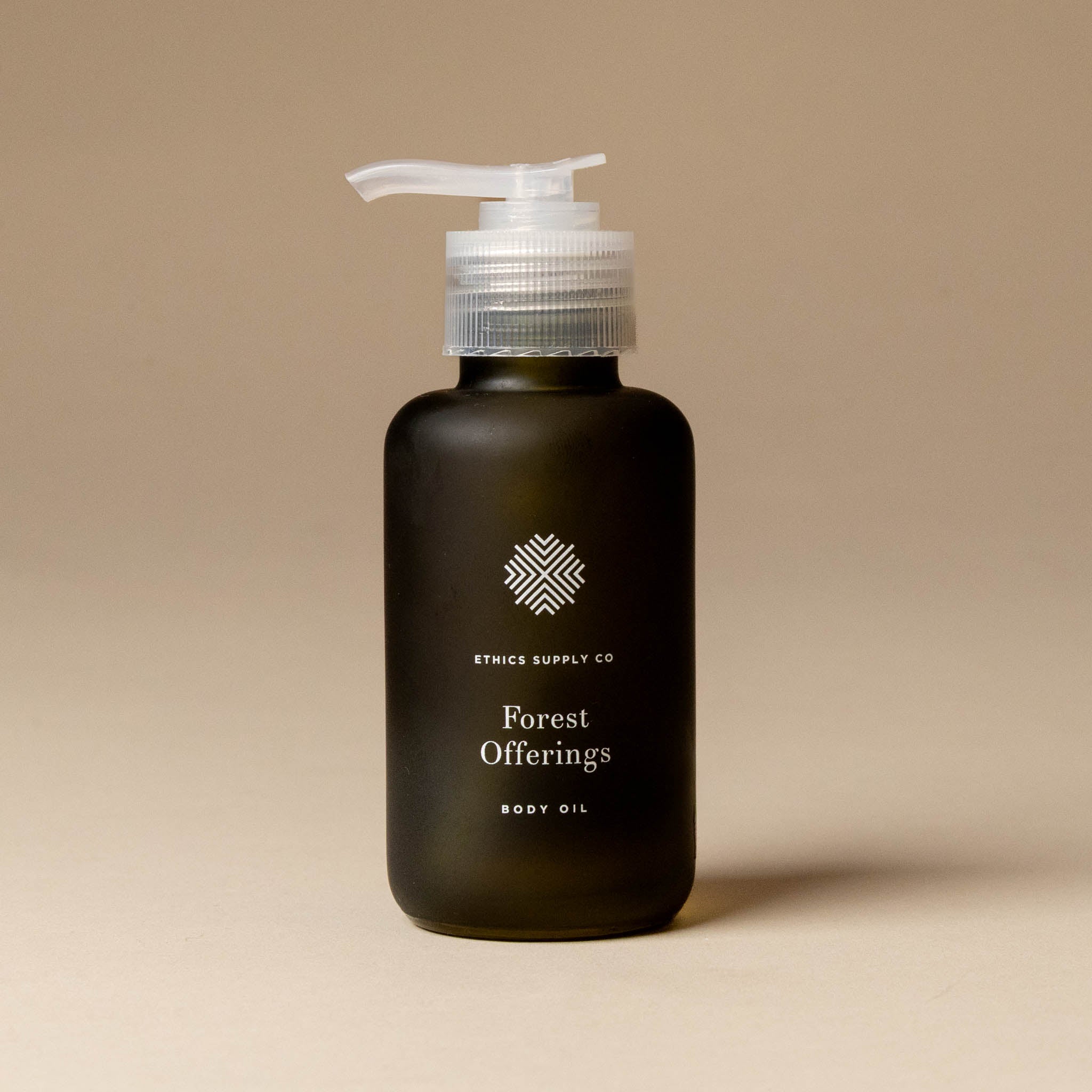 Black bottle of 'Forest Offerings' body oil with a pump on a beige background