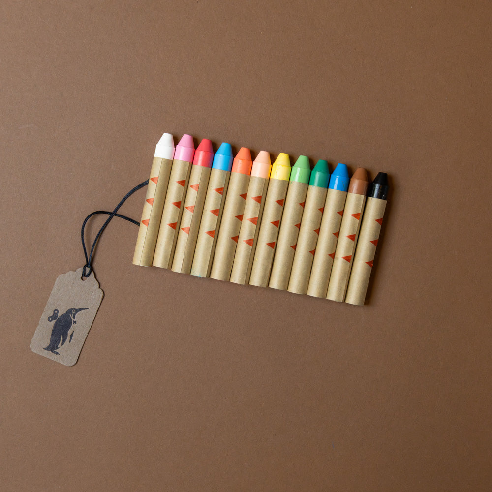 Buttery-Soft-Rice-Wax-Art-Crayons-12-Colors Set of colorful wooden crayons with a tag on a brown background