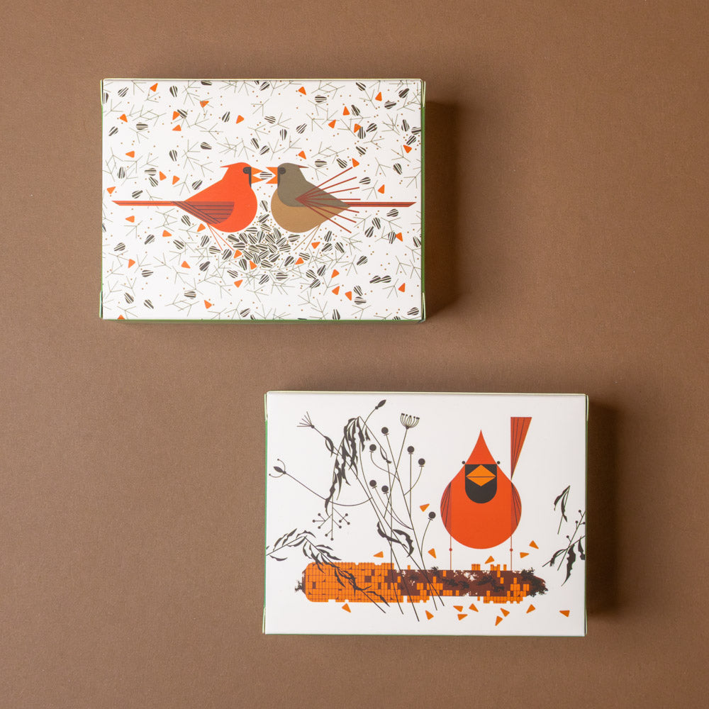 Two decorative boxes with bird illustrations on a brown background