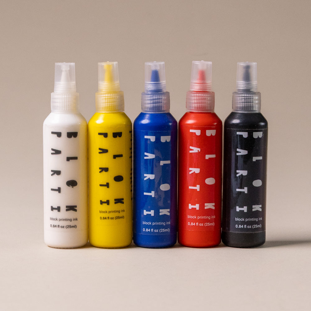 create-your-own-block-print-stationary-kit-abstract Five spray bottles of different colors with 'PARTIK' branding on a beige background