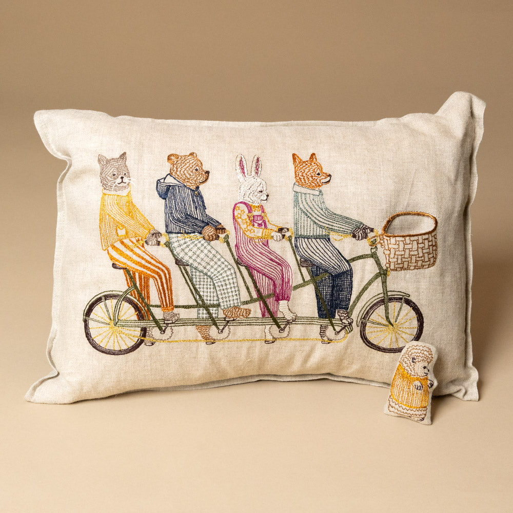 embroidered-pocket-pillow-tandem-bike-buddies of animals on a bicycle, on a beige background.