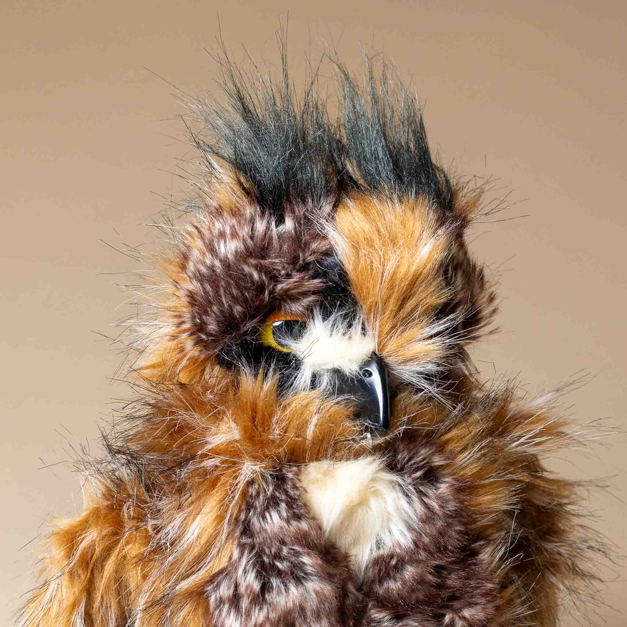 great-horned-owl-hand-puppet Close-up of a stuffed owl with detailed feathers on a beige background