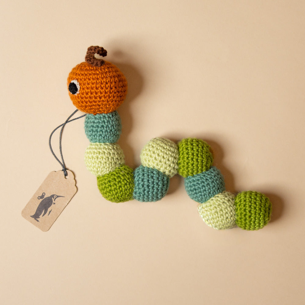 hand-crocheted-caterpillar-rattleon a beige background