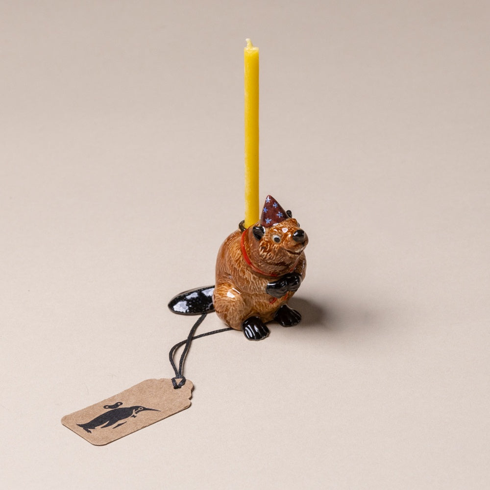 heirloom-porcelain-cake-topper-beaver Ceramic animal-shaped candle holder with a yellow candle on a beige background