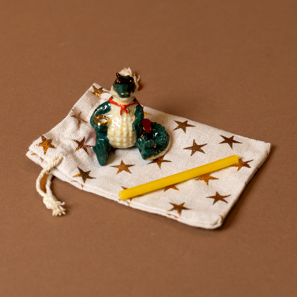 heirloom-porcelain-cake-topper-super-gator with a candle on a star-patterned cloth with a brown background