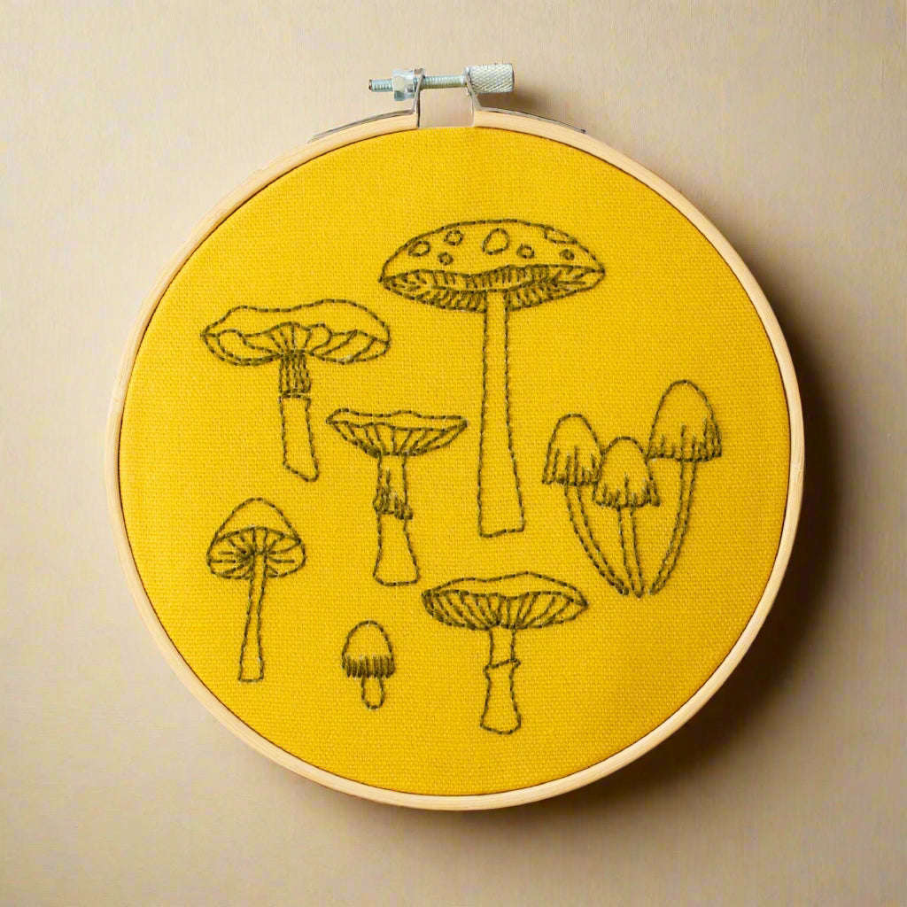 Embroidery hoop with mushroom designs on yellow fabric