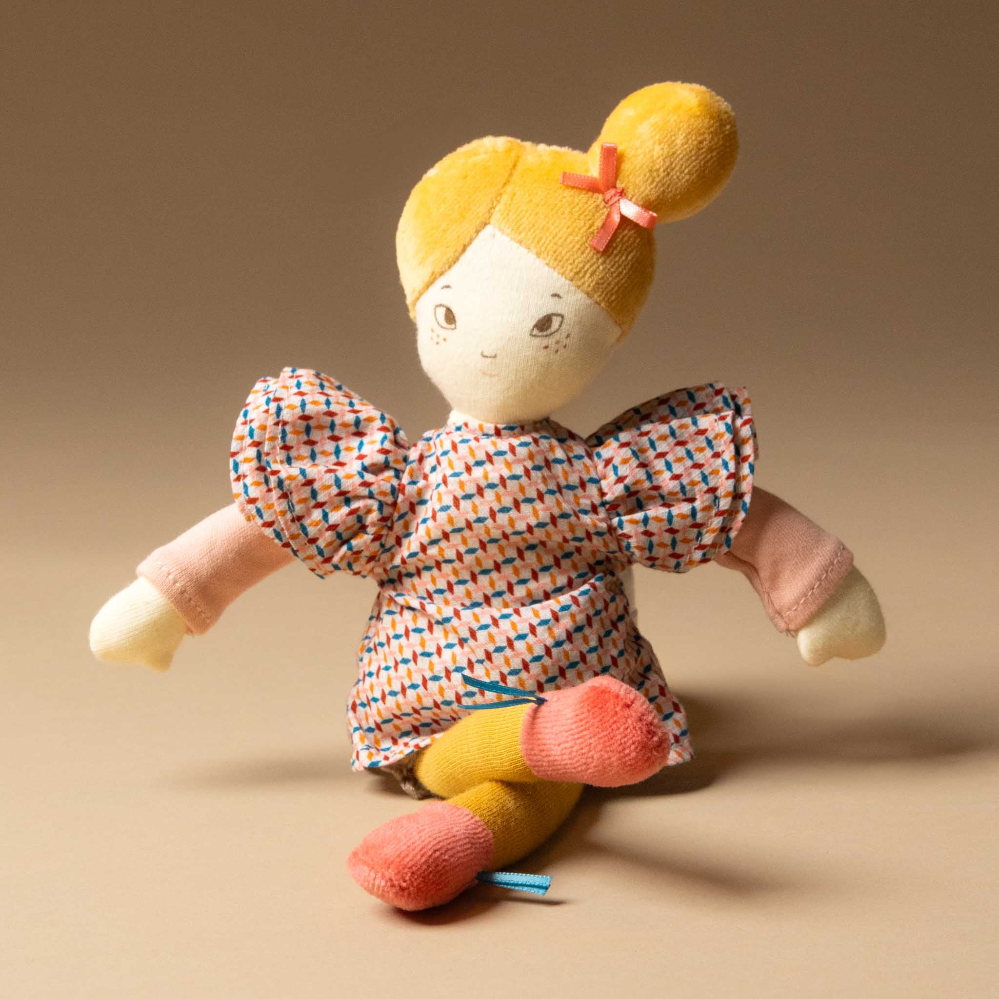les-parisiennes-petite-agathe-doll-yellow-velvet-hair-and-leggings-patterned-dress-pink-hair-bow-sitting
