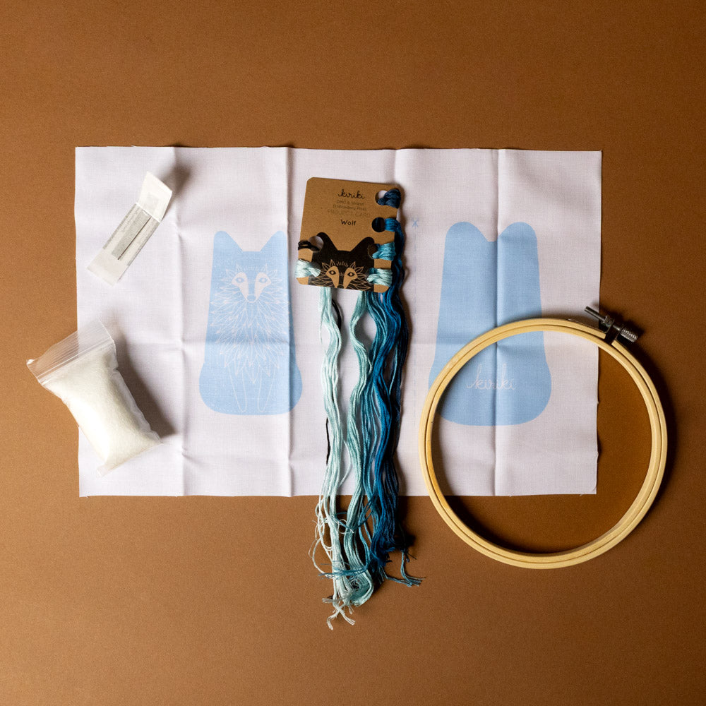 make-your-own-embroidered-animal-kit--wolf Embroidery kit with hoop, thread, and fabric on a brown background