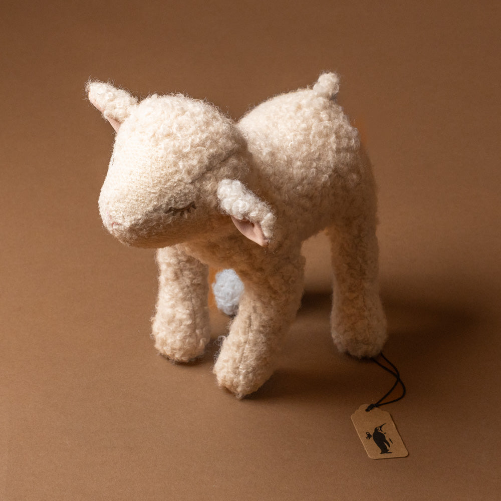 mary-the-lamb-large Stuffed animal toy with a tag on a brown background