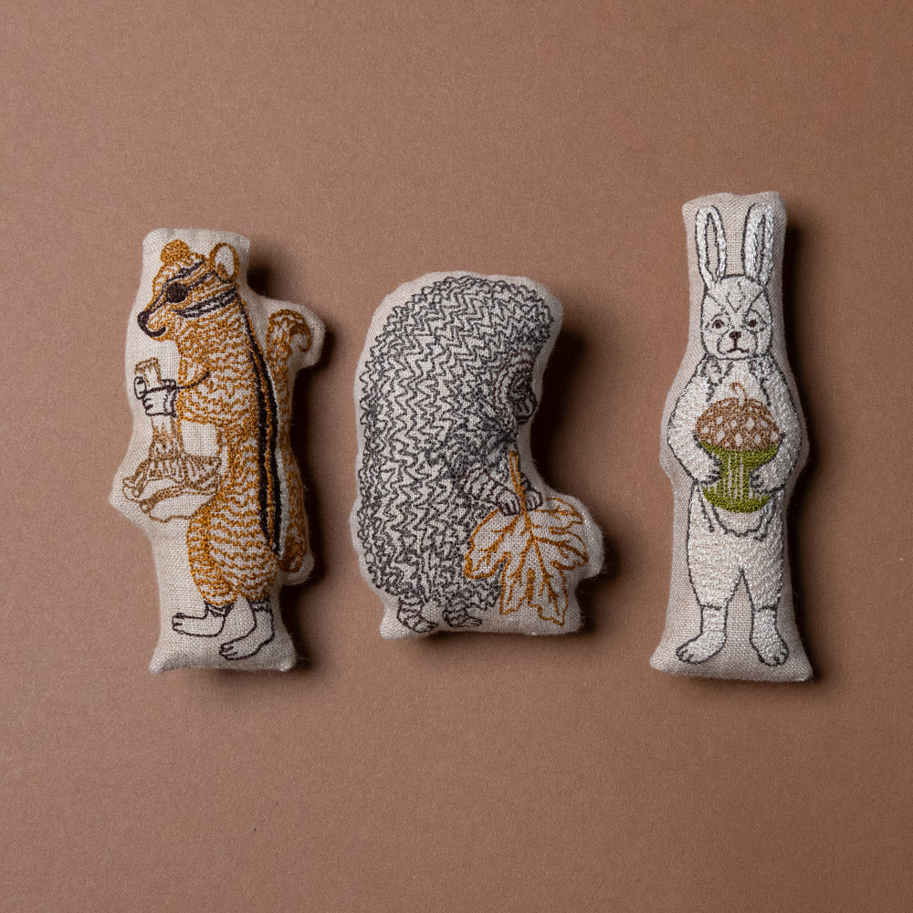 mushroom-forest-pocket-pillow Three embroidered animal figurines on a brown background