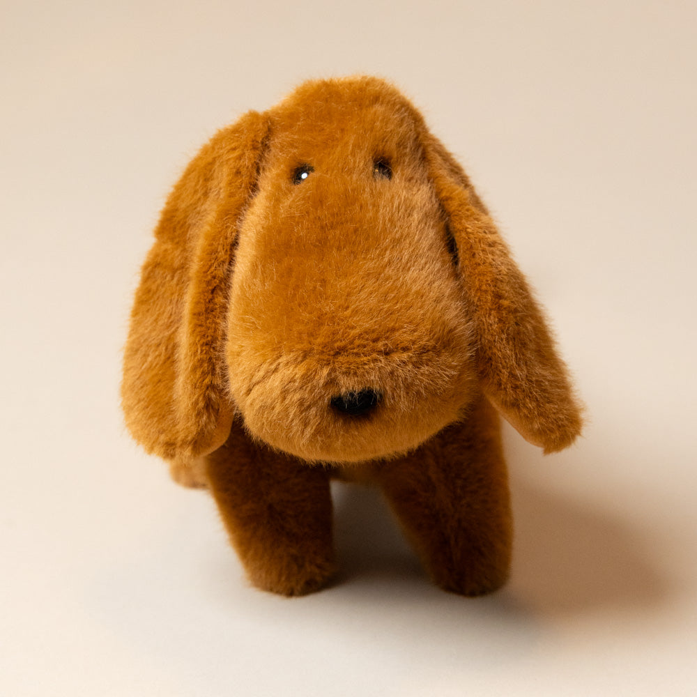 Brown plush toy resembling a dog with long ears on a beige background
