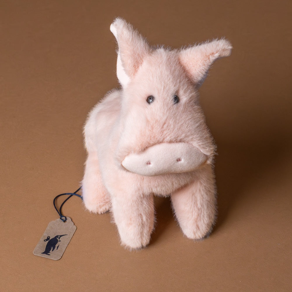 muzzle-peter-pig-large Plush toy pig with a tag on a brown background