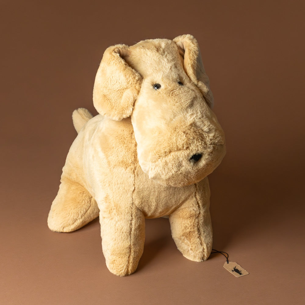 muzzle-tim-tan-pup-jumbo Beige stuffed dog toy on a brown background