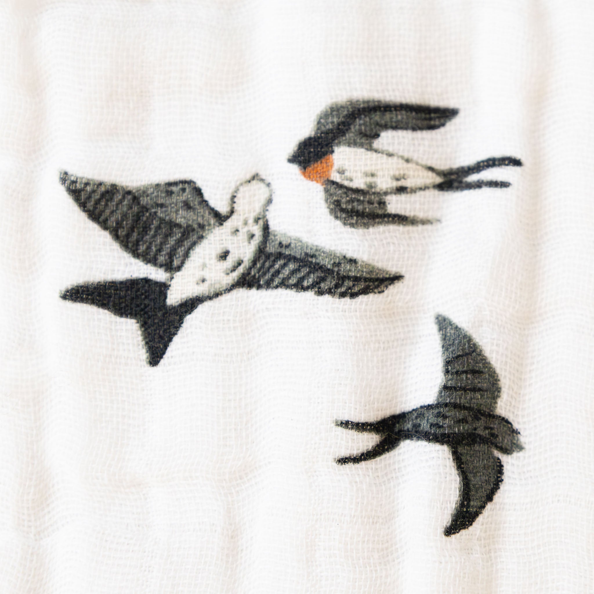 organic-cotton-muslin-blanket-swallows-pattern-black-and-white-with-orange-detail