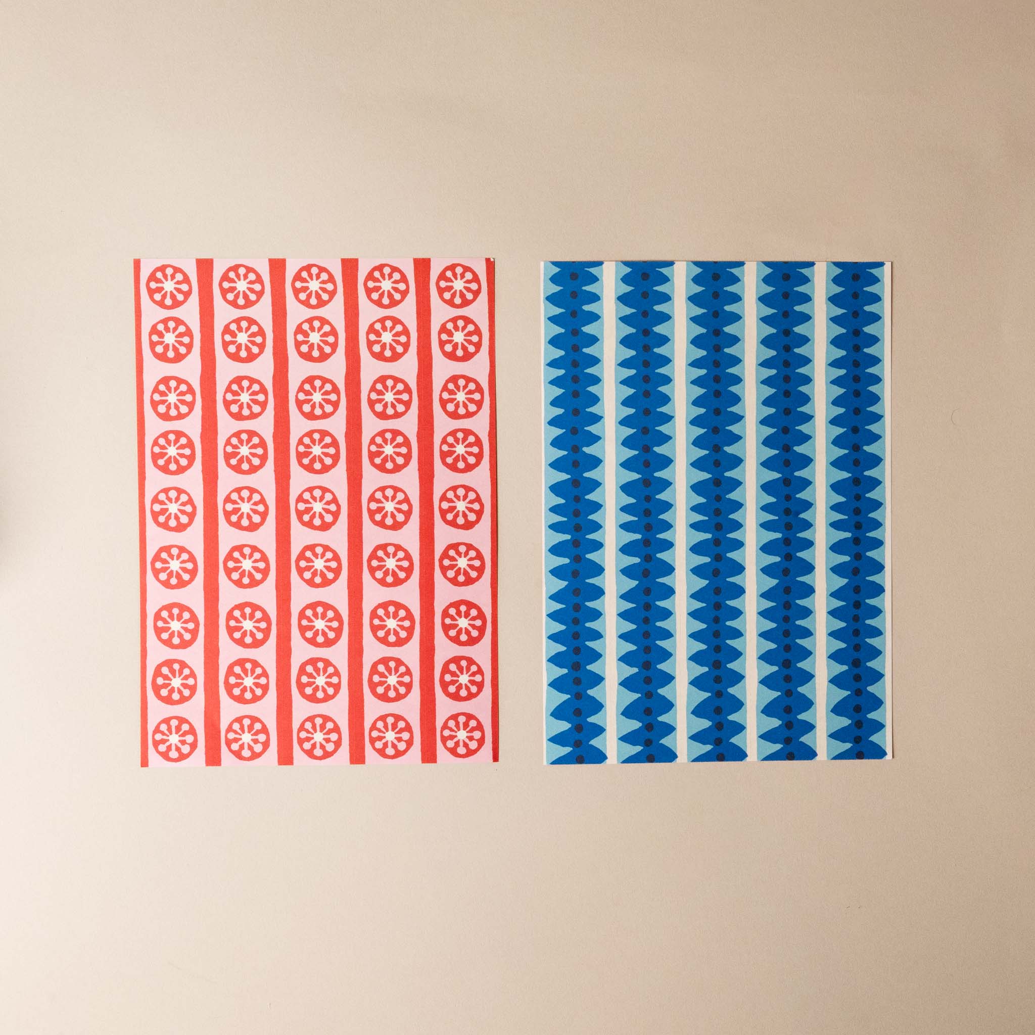 paperchain--tea-party-Two patterned panels, one red with geometric shapes and one blue with wavy lines, on a beige background.