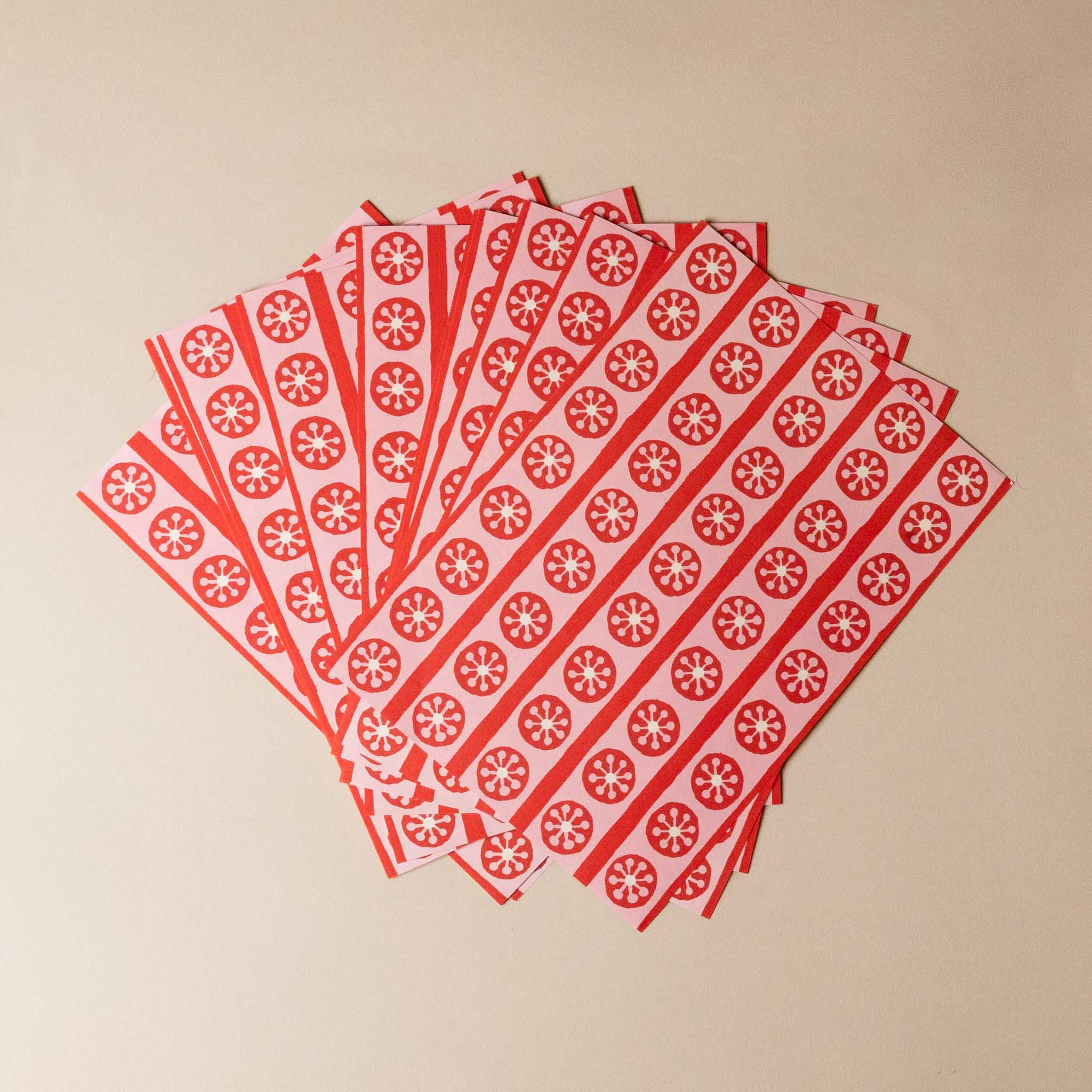 paperchain--tea-party-Stack of red and white patterned paper strips on a beige background