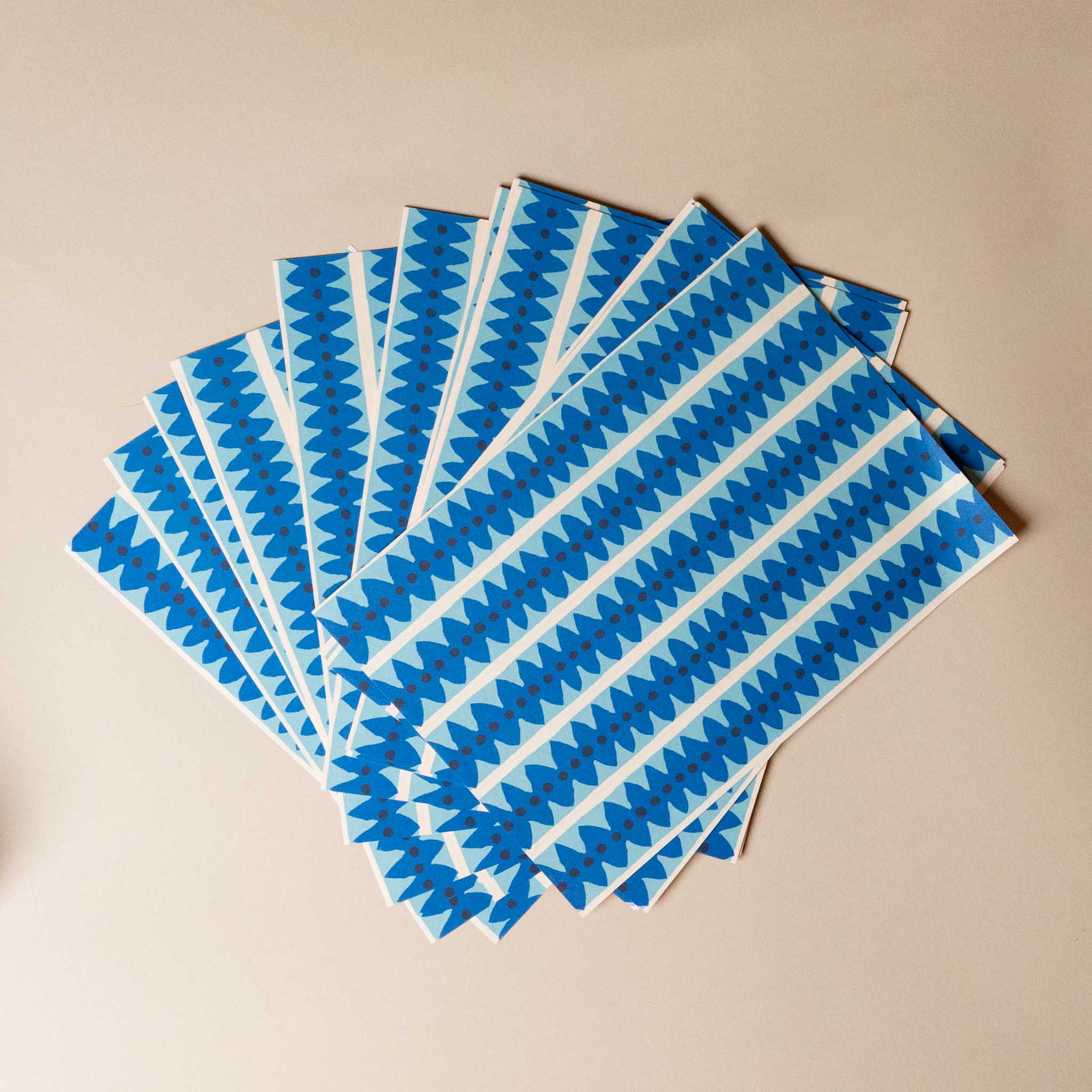 paperchain--tea-party-Set of blue and white patterned paper sheets on a beige background