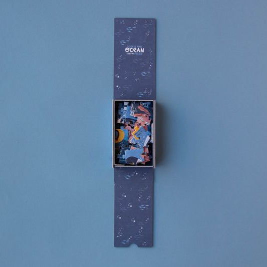 petite-36-piece-observation-puzzle-ocean Colorful puzzle pieces in a blue box on a blue background