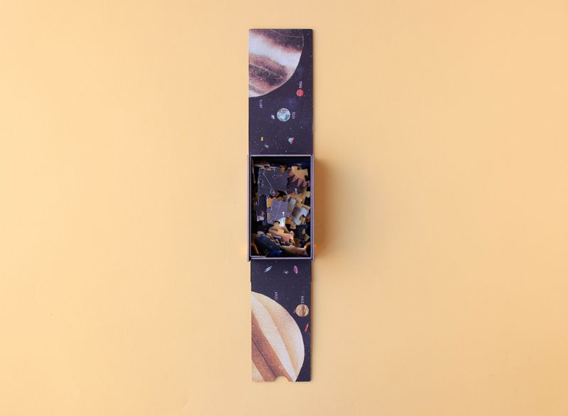 petite-24-piece-observation-puzzle-planets Unfolded space-themed puzzle box with packaging on a beige background