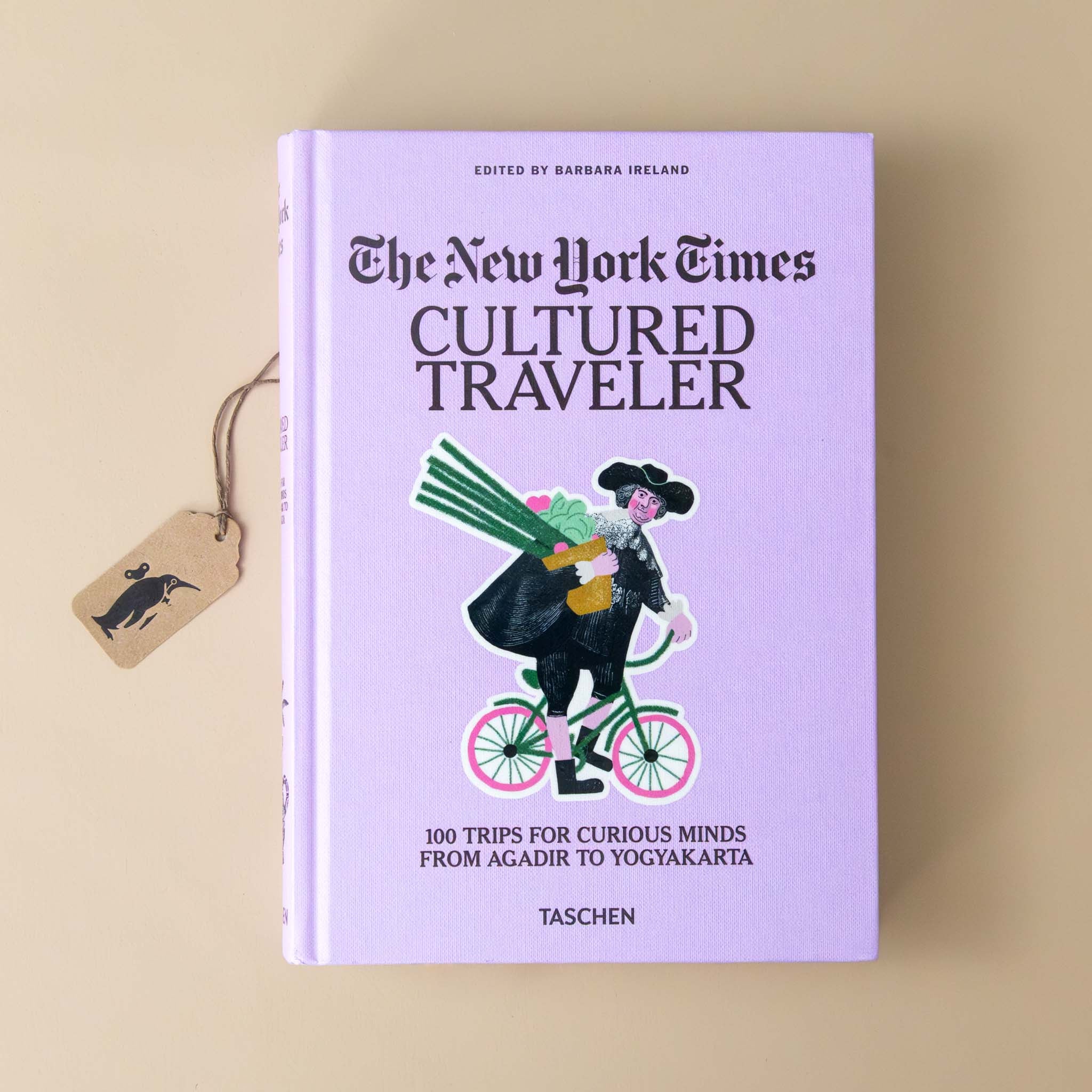 the-new-york-times-cultured-traveler-lavender-cover-with-revolutionary-figure-on-a-bike-with-a-bag-full-of-farmers-market-finds