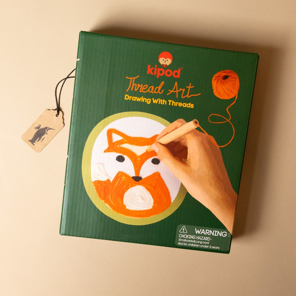 green-box-Thread Art kit with a hand holding a thread, on a beige background