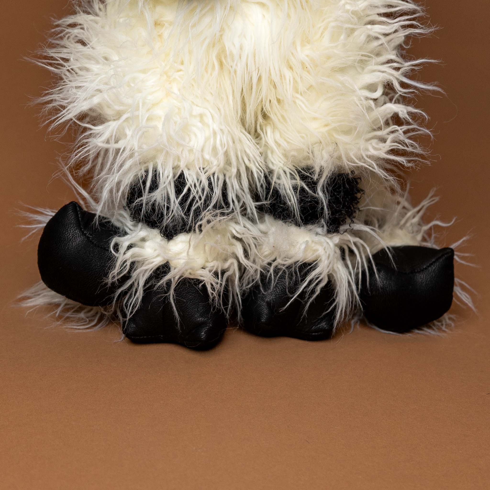 valais-black-nose-sheep-hand-puppet Close-up of a fluffy white and black animal toy on a brown background