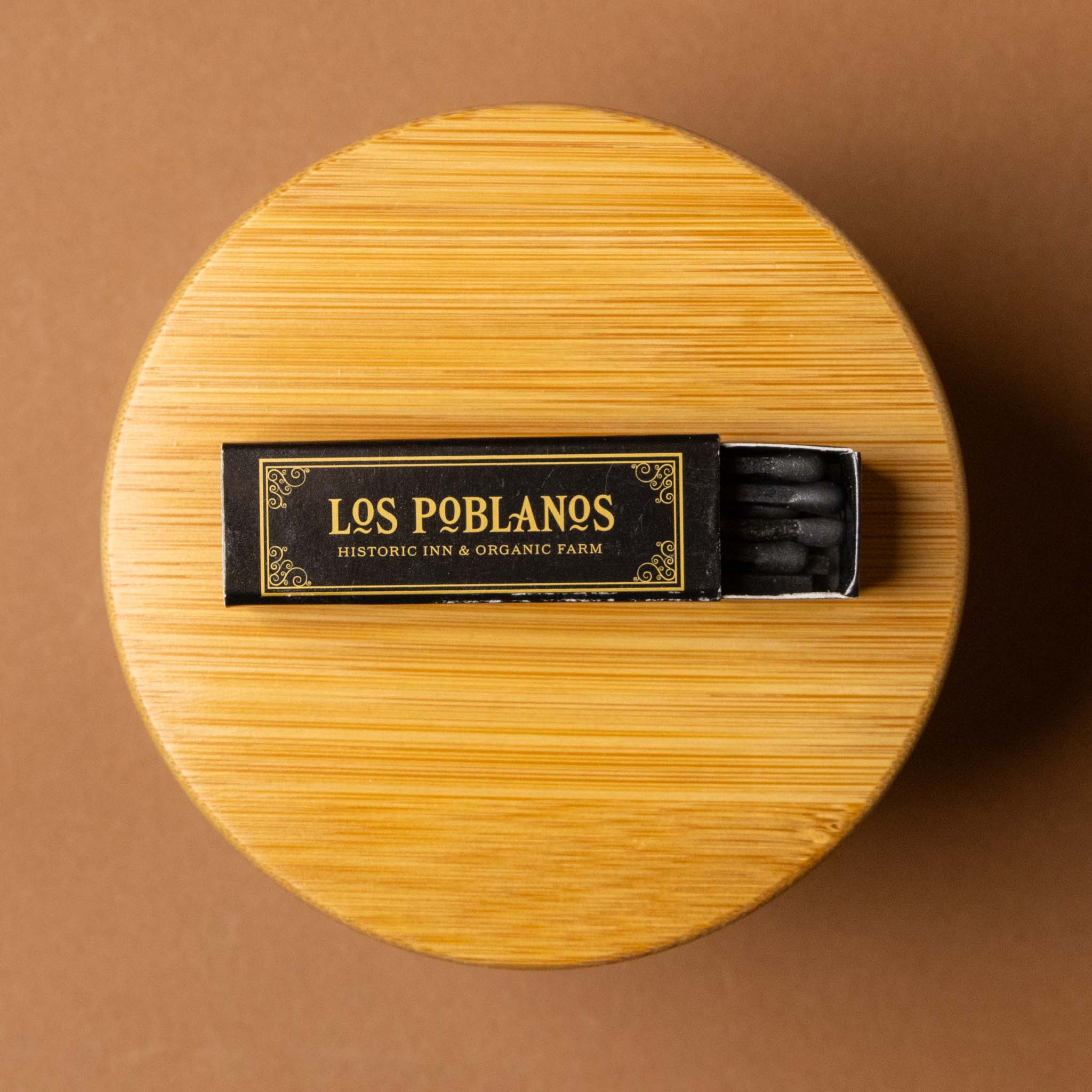 Wooden box with a matchbox labeled 'Los vela-del-jardin-candle-Poblanos' on a brown background