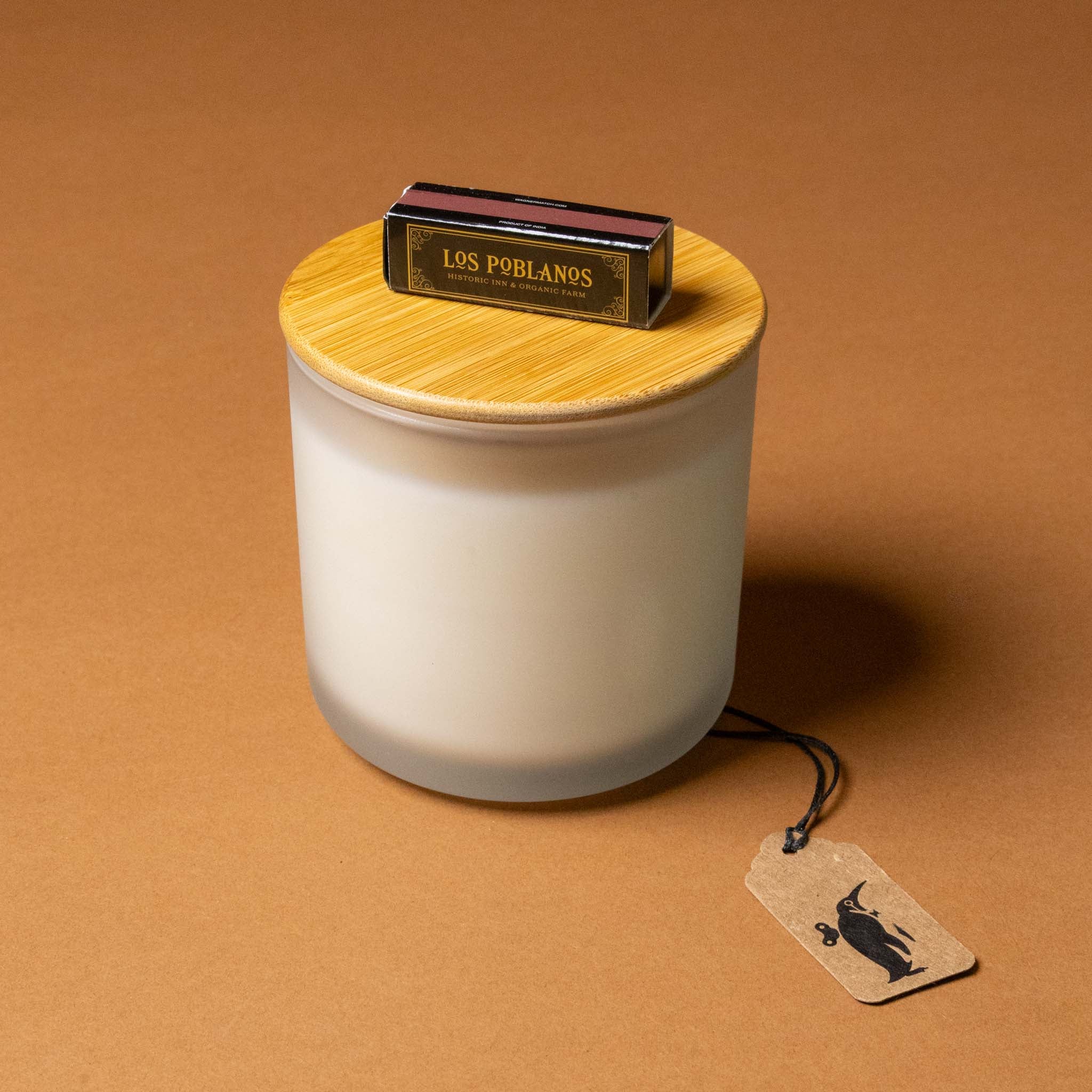 vela-del-jardin-candle-White candle with wooden lid and 'Los Poblanos' packaging on a brown background