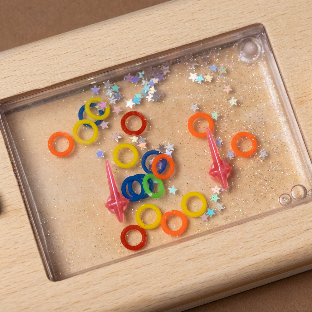 Colorful ring toys on a wooden tray with star-shaped confetti