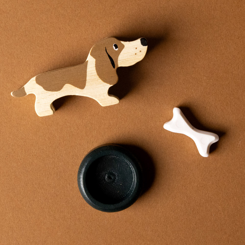 wooden-pet-play-set-dog Wooden dog toy, black ball, and bone-shaped toy on a brown background