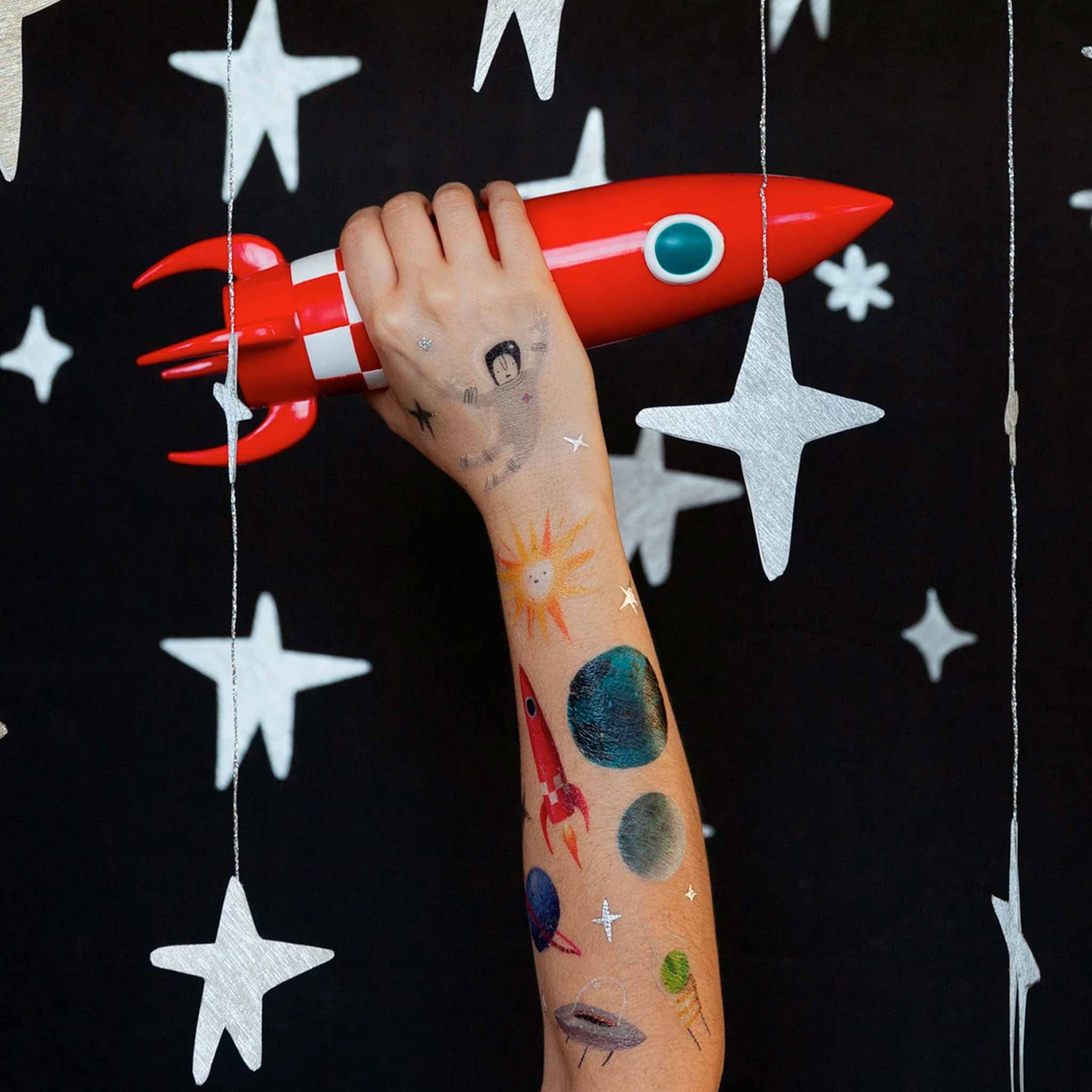 space-themed-tattoos-on-light-skinned-model-holding-red-rocket