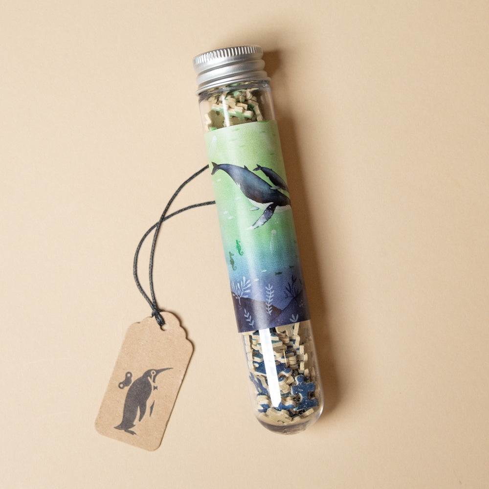 150-piece-micro-puzzle-whales tube with decorative label and contents on a beige background