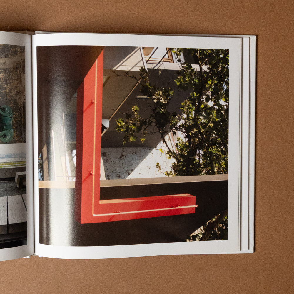 alphabet-everywhere Open book showing a photograph of a red frame L with greenery on a brown background