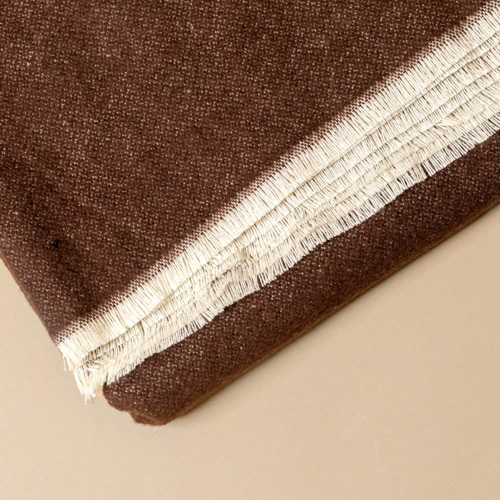aspen-throw-chocolate Brown fabric with a white eyelash fringe on a beige background