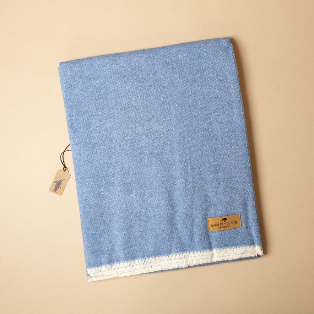 aspen-throw-niagra Blue fabric with a brand tag on a beige background