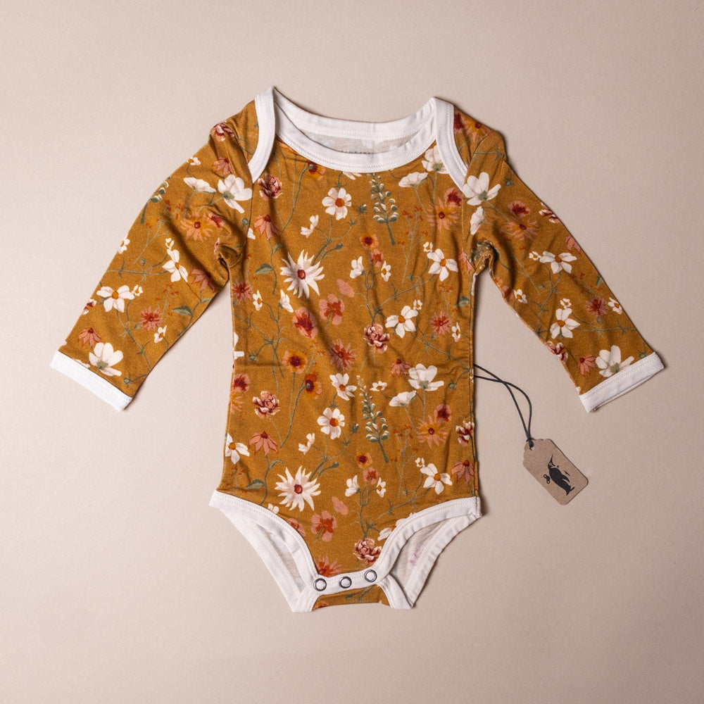bamboo-long-sleeve-stretch-onesie-wildflower Floral-patterned baby onesie on a beige background