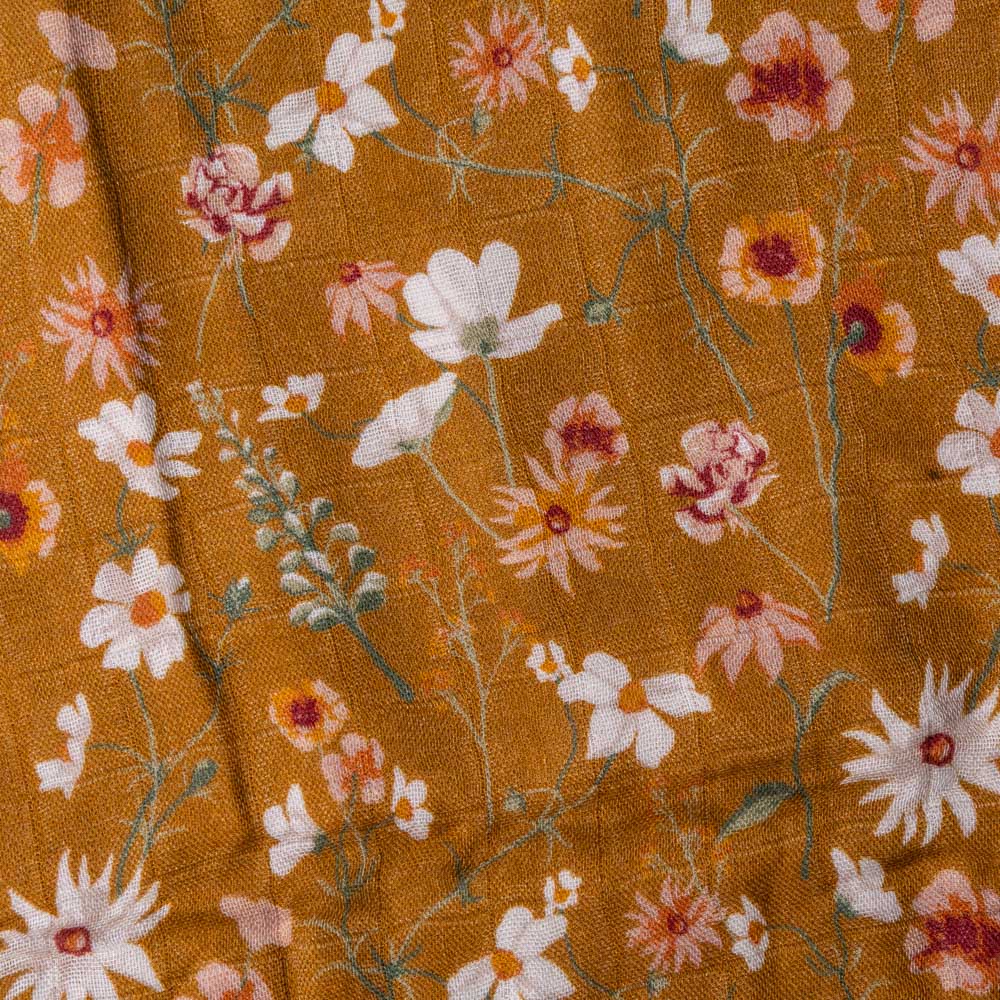 bamboo-swaddle-wildflower Close-up of floral fabric with white, pink, and orange flowers on a mustard background