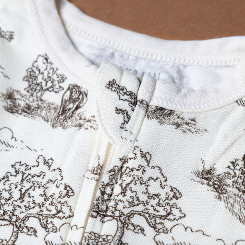 bamboo-zipper-pajamas-meadow-toile Close-up of a baby onesie with tree pattern on a plain background