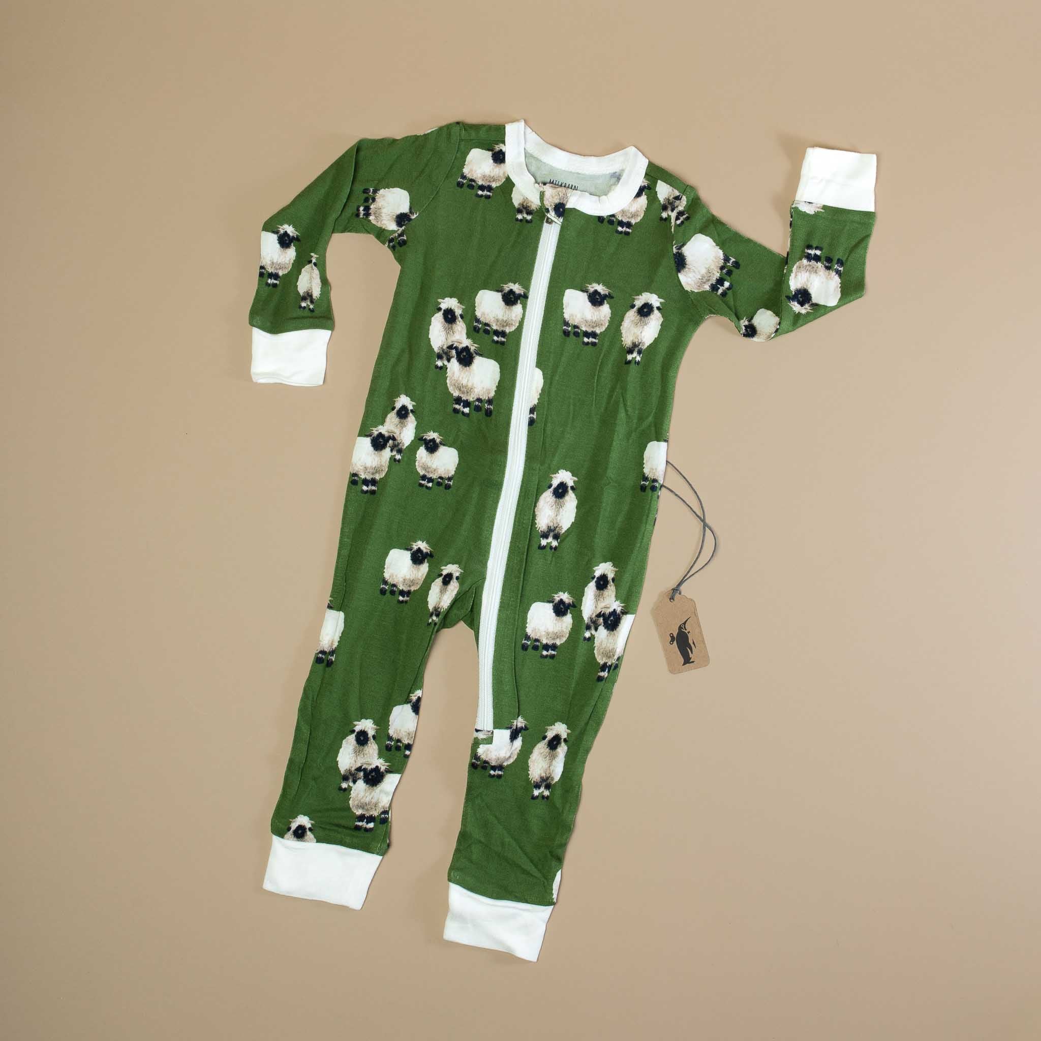 bamboo-zipper-pajamas-valais-sheep Green onesie with sheep pattern on a beige background