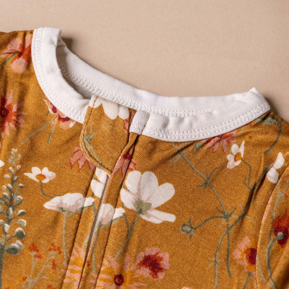 bamboo-zipper-pajamas-wildflower Close-up of a garment with a floral pattern and white collar on a beige background
