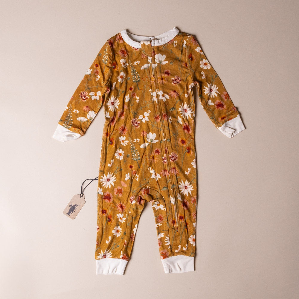 bamboo-zipper-pajamas-wildflower Floral-patterned baby onesie on a beige background