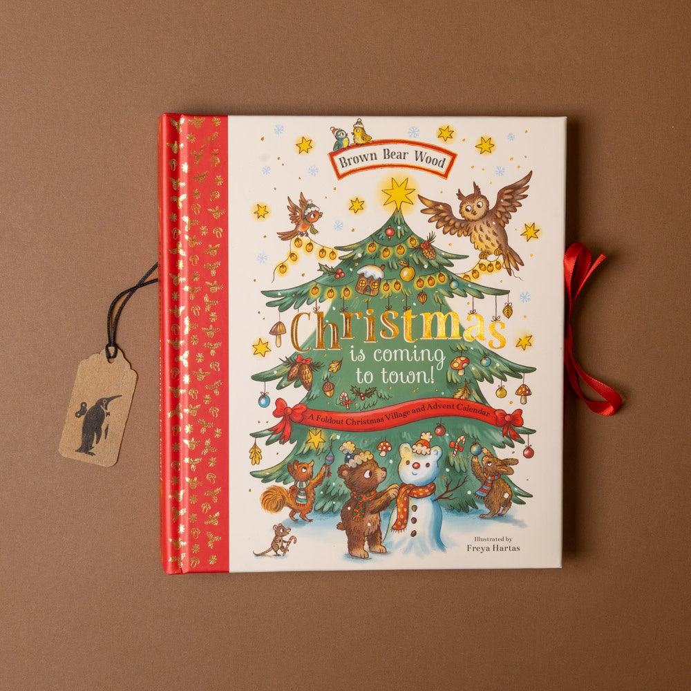 Children's book titled 'Christmas is coming to town!' with a Christmas tree and animals on the cover, on a brown background.