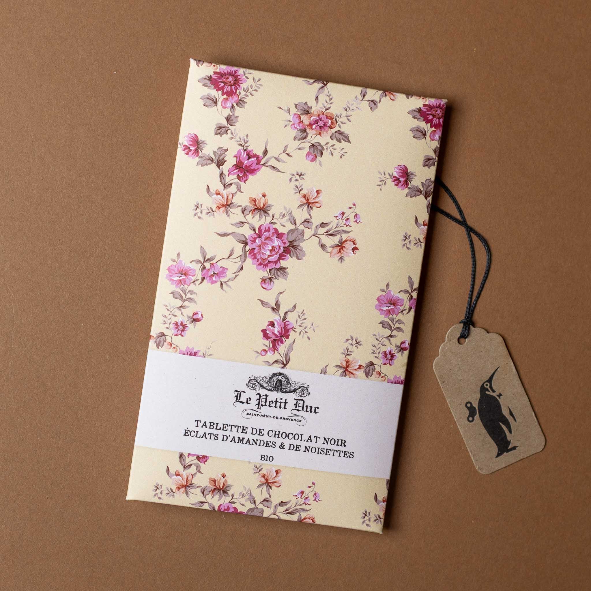 chocolat-noir-bar-almonds-and-hazelnuts Floral packaging with a tag on a brown background