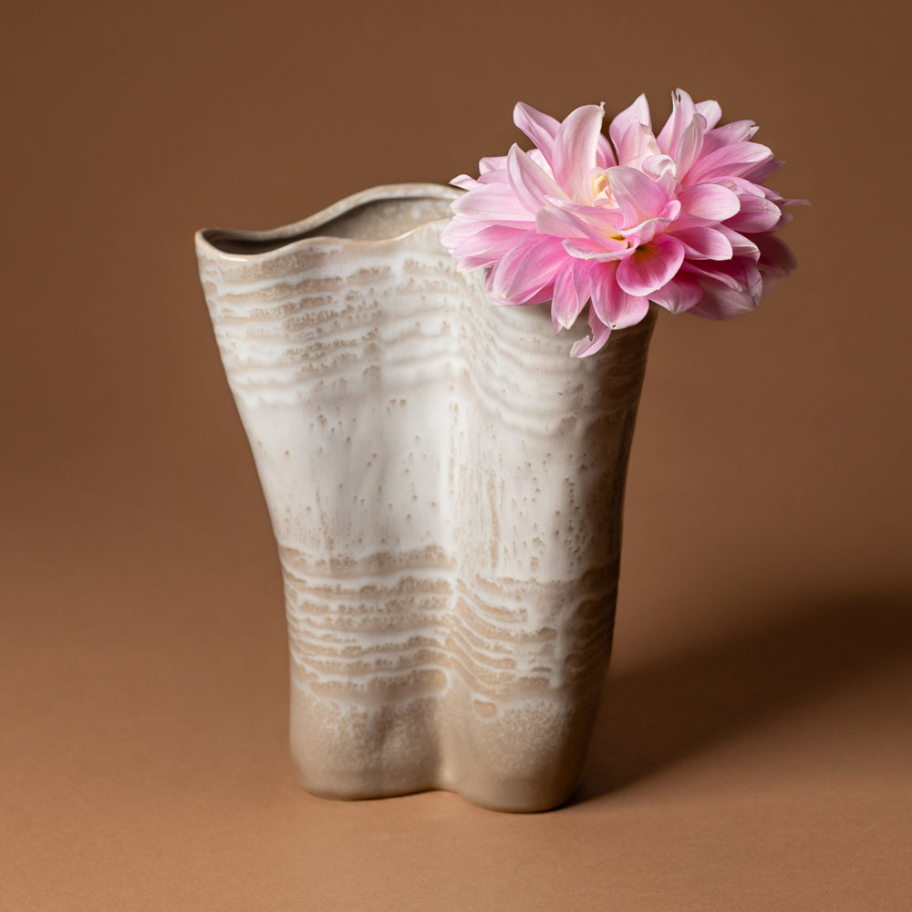 claribel-vase-tall Ceramic vase with a textured surface holding a pink flower against a brown background